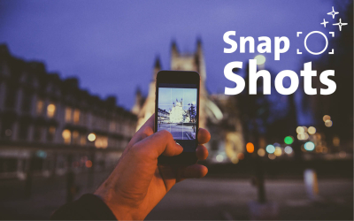 Hand mit Handy und Stadtbild im Hintegrund